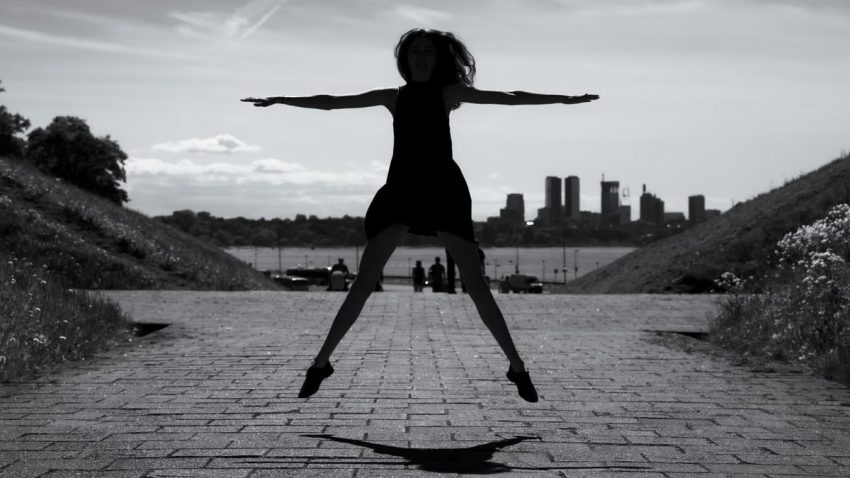 A dynamic black and white silhouette of a woman jumping with arms outstretched in Tallinn, Estonia.